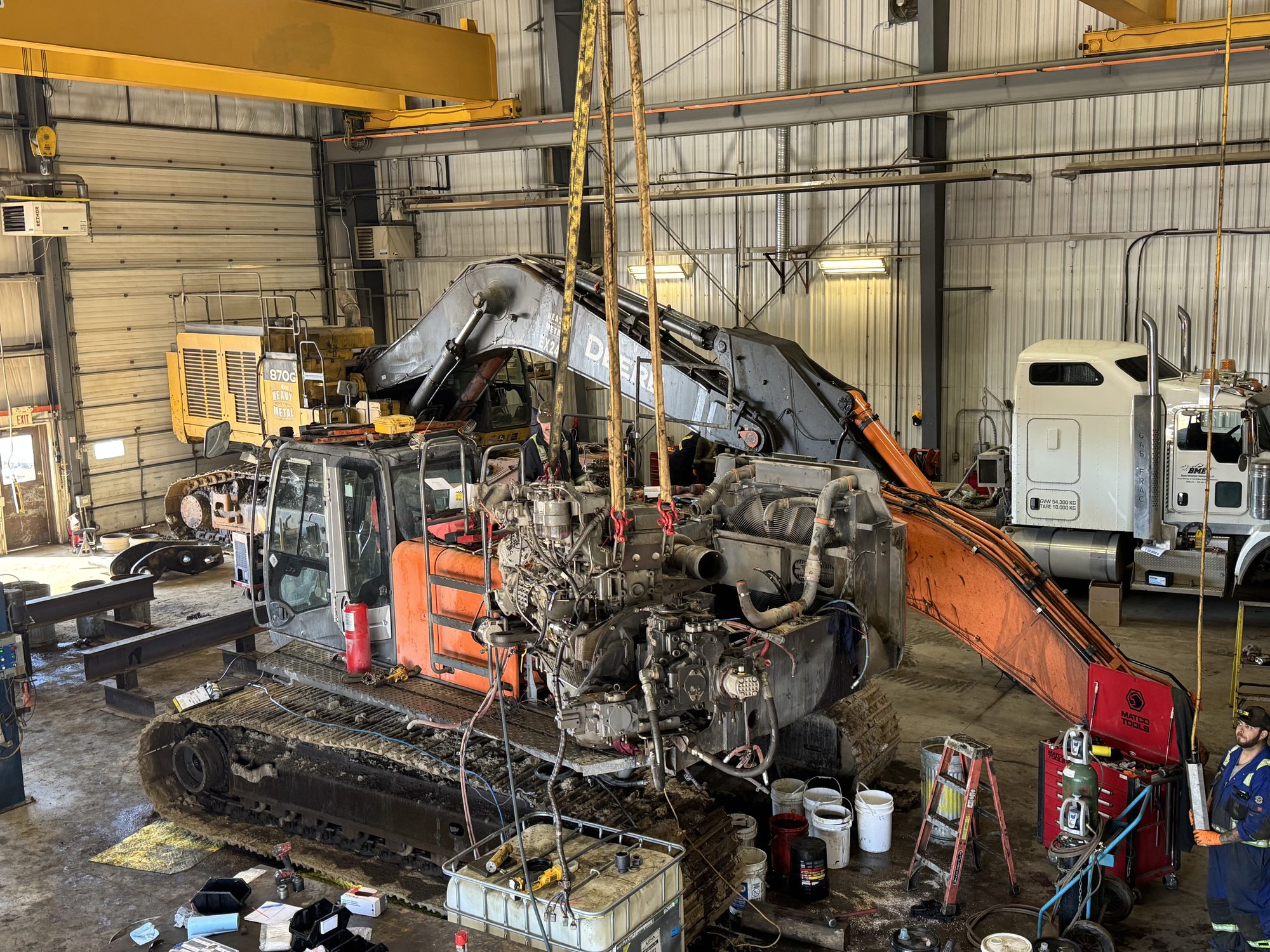 Engine being lifted from a Doosan excavator under the 20-ton overhead crane